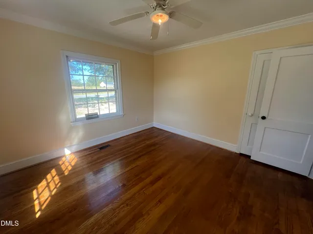 a view of an empty room with wooden floor and a window