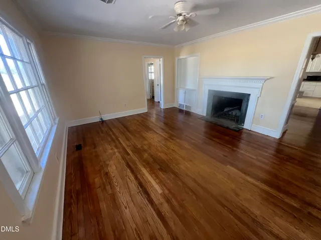 a view of an empty room with wooden floor and a window