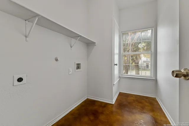 an empty room with wooden floor chandelier fan and windows