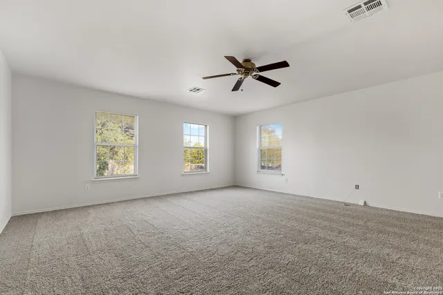 wooden floor in an empty room with a chandelier fan