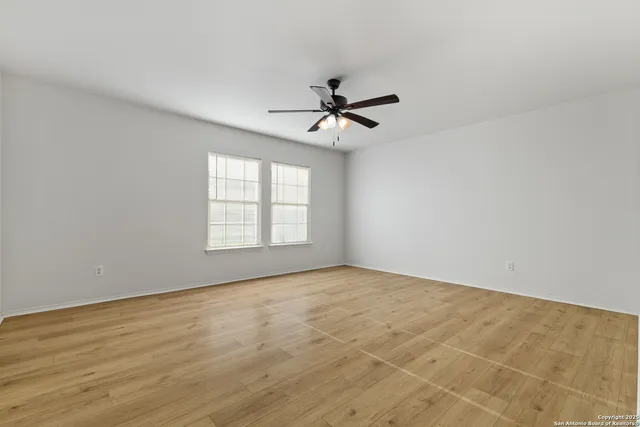 a view of empty room with wooden floor and fan
