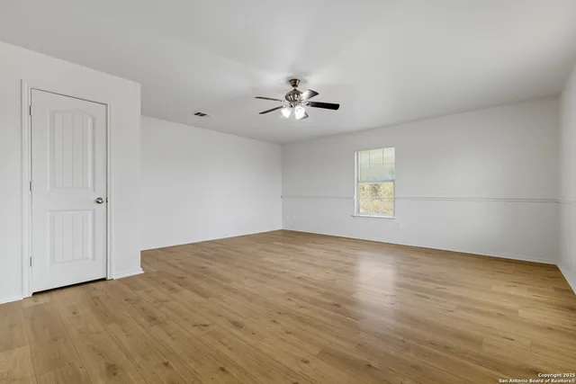 a view of empty room with wooden floor and ceiling fan