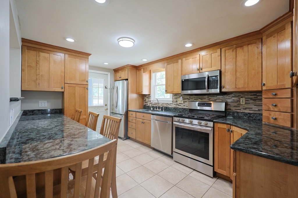 20 Kent Street Saugus, MA 01906 - Photo 4 of 41 a kitchen with stainless steel appliances granite countertop a stove top oven a sink dishwasher a microwave oven and a refrigerator with wooden floor