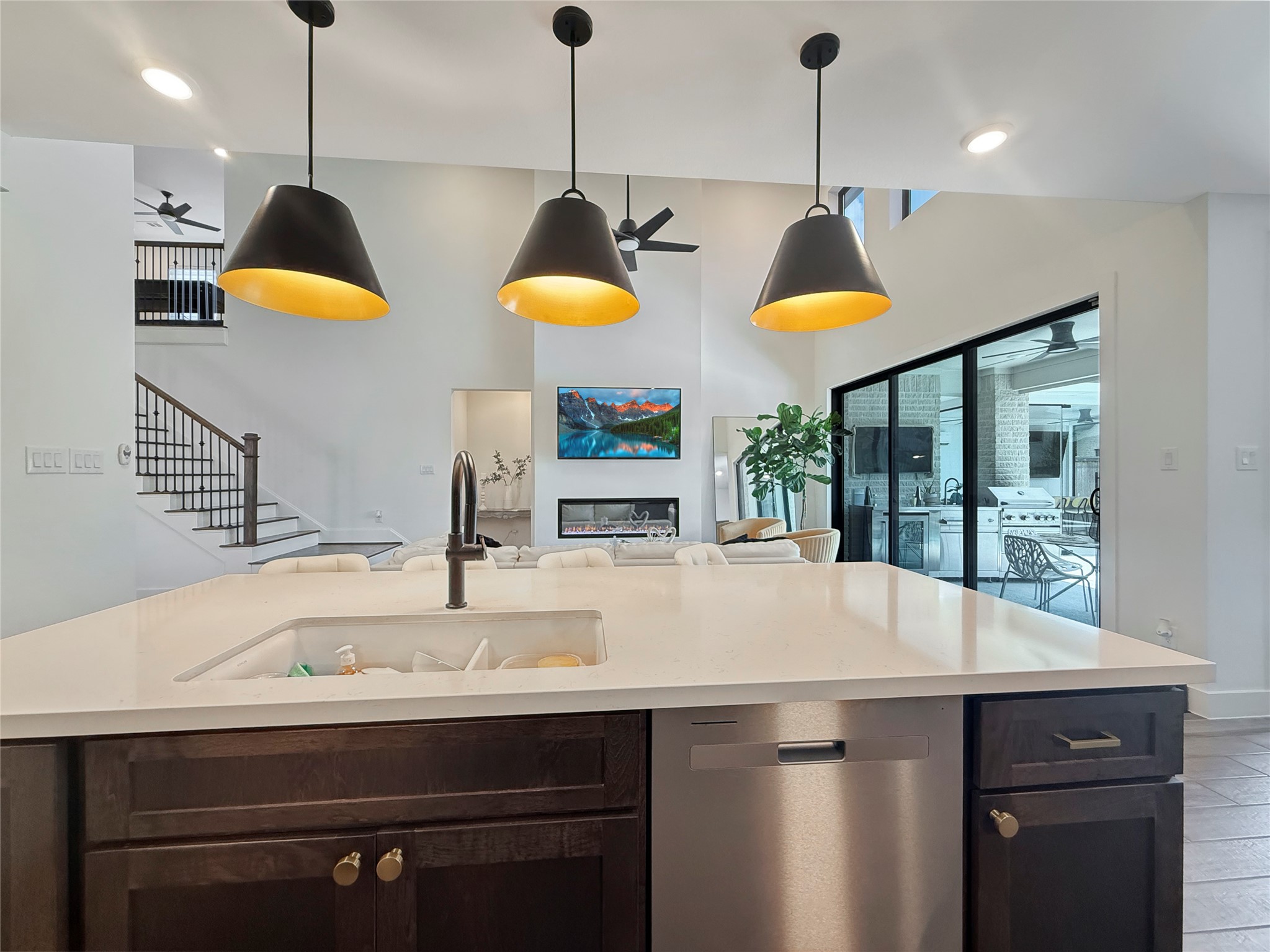 26918 Swanborough Road Spring, TX 77389 - Photo 16 of 50 The chef's kitchen anchors the open-concept living space, featuring a sprawling quartz waterfall island, designer matte-black pendant lighting, and a seamless flow into the soaring two-story living room with modern fireplace wall.