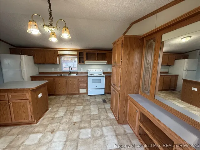 a large kitchen with stainless steel appliances kitchen island granite countertop a stove refrigerator and cabinets