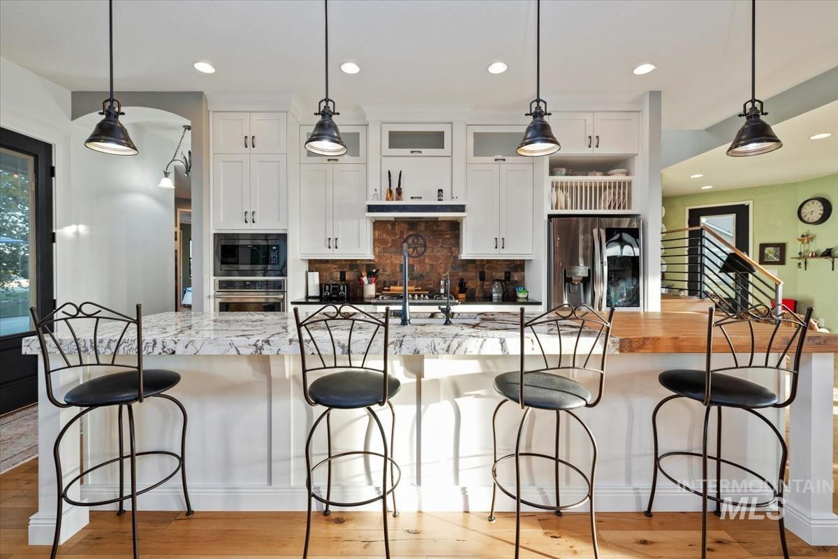 11326 West Rio Road Caldwell, ID 83607 - Photo 12 of 50 Kitchen featuring white cabinets, hanging light fixtures, a spacious island, decorative backsplash, and recessed lighting