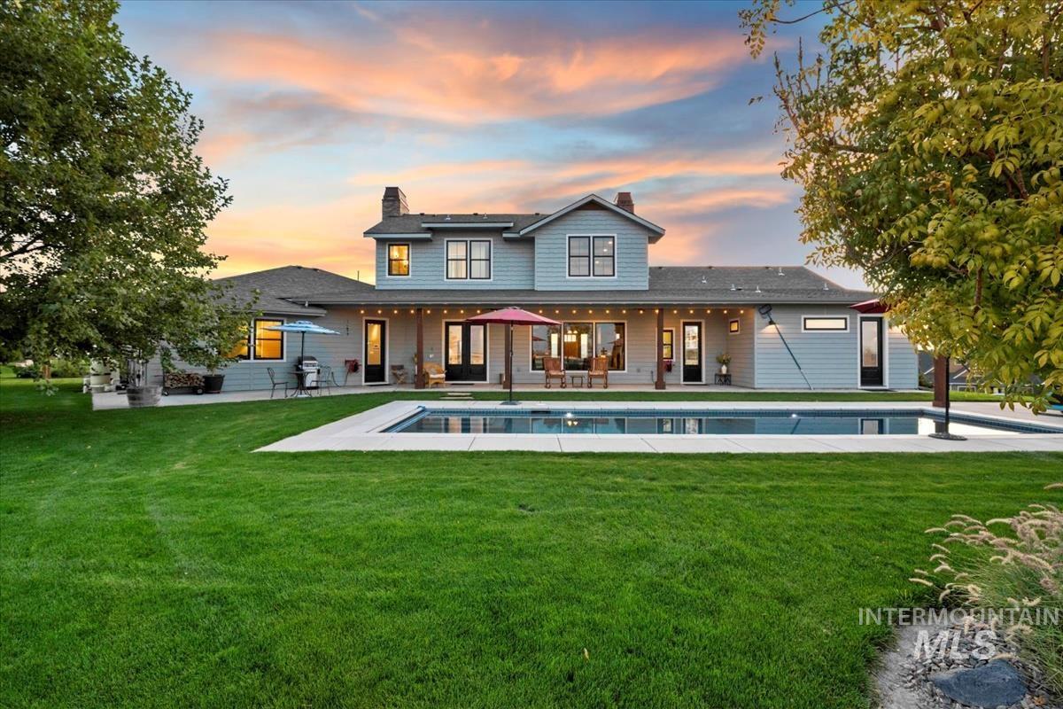 11326 West Rio Road Caldwell, ID 83607 - Photo 34 of 50 Back of house at dusk with a patio, an outdoor pool, a chimney, and a yard