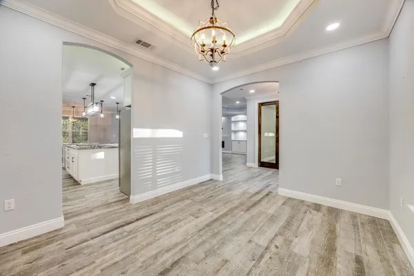an empty room with wooden floor a ceiling fan a fireplace and windows