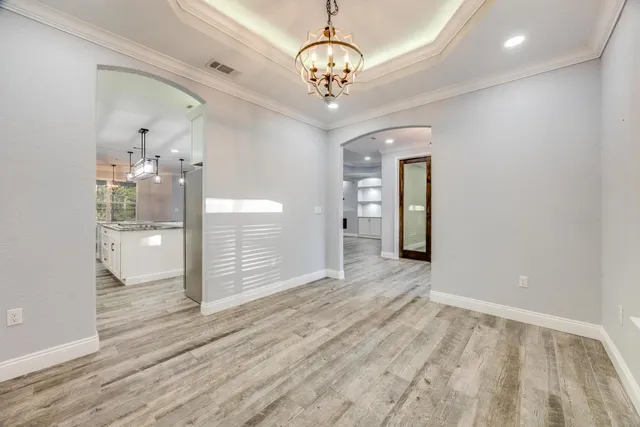 an empty room with wooden floor a ceiling fan a fireplace and windows