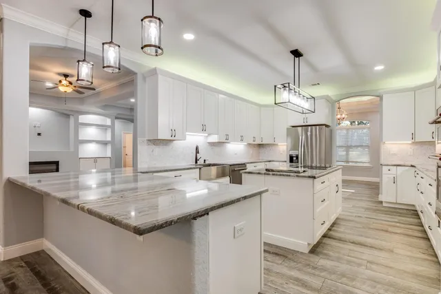 a kitchen with granite countertop a refrigerator stove and white cabinets
