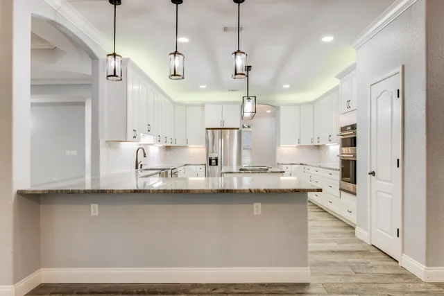 a kitchen with granite countertop white cabinets and stainless steel appliances