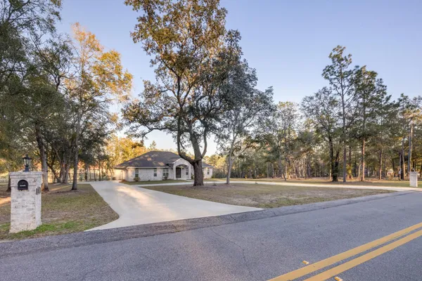 an empty room with wooden floor chandelier fan and windows