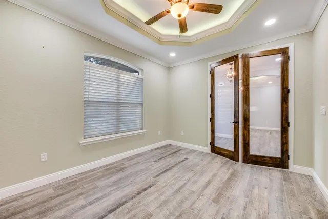 a view of empty room with wooden floor and kitchen view