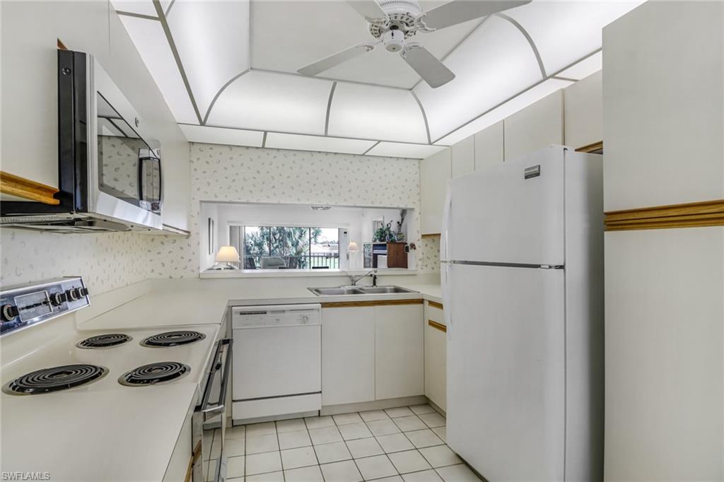 780 Augusta Boulevard, Unit C204 Naples, FL 34113 - Photo 14 of 40 a kitchen with a refrigerator a stove a sink and cabinets