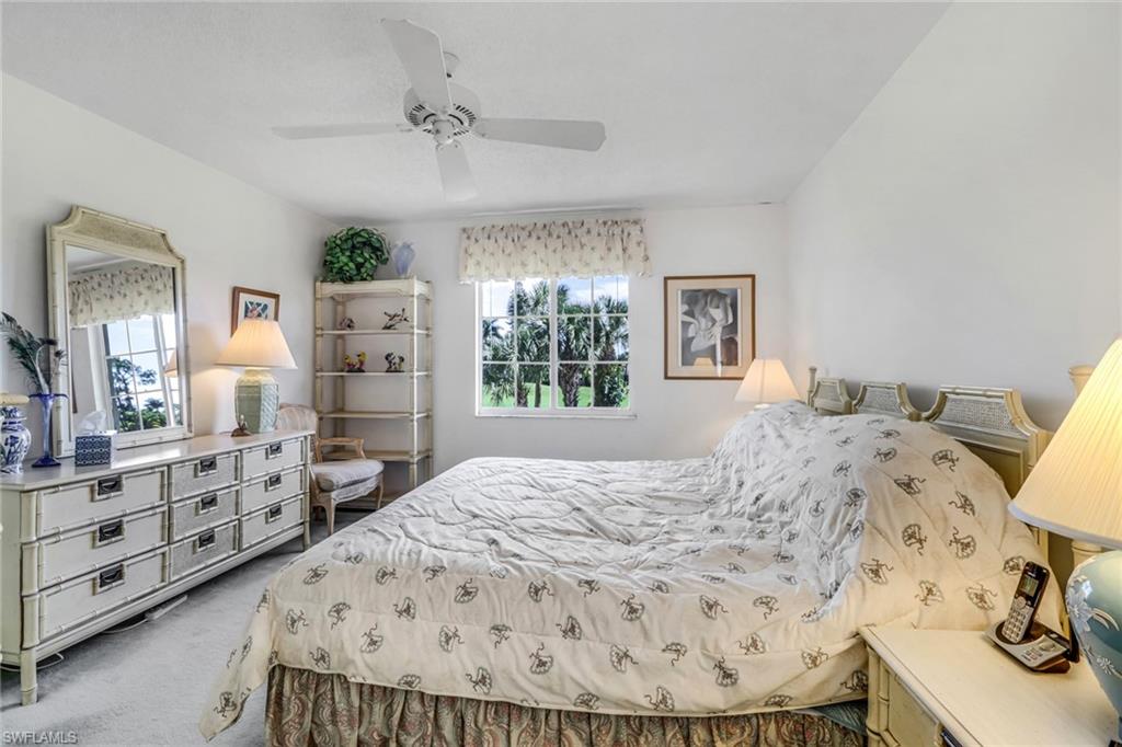 780 Augusta Boulevard, Unit C204 Naples, FL 34113 - Photo 17 of 40 a bedroom with a bed and dresser with mirror