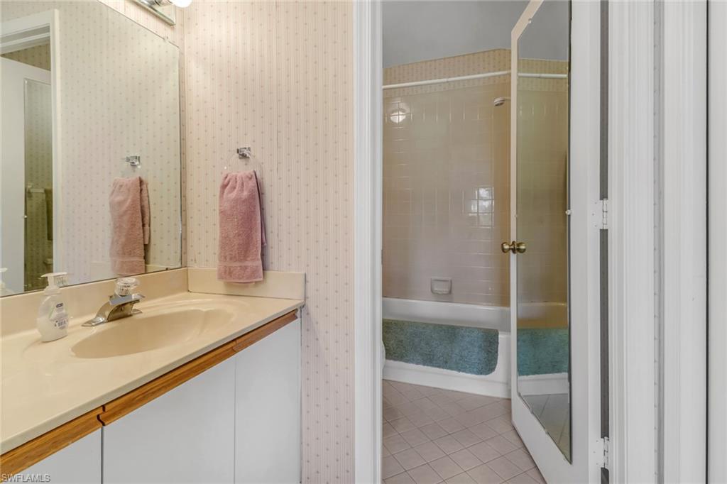 780 Augusta Boulevard, Unit C204 Naples, FL 34113 - Photo 20 of 40 a bathroom with a shower sink and mirror