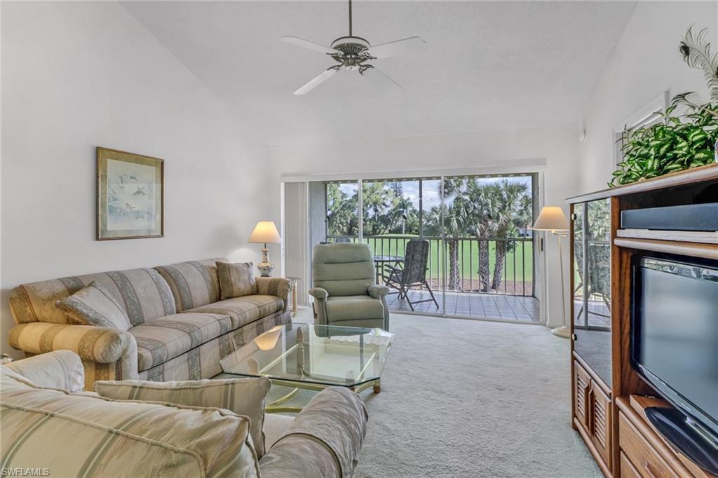 780 Augusta Boulevard, Unit C204 Naples, FL 34113 - Photo 6 of 40 a living room with furniture a flat screen tv and a floor to ceiling window