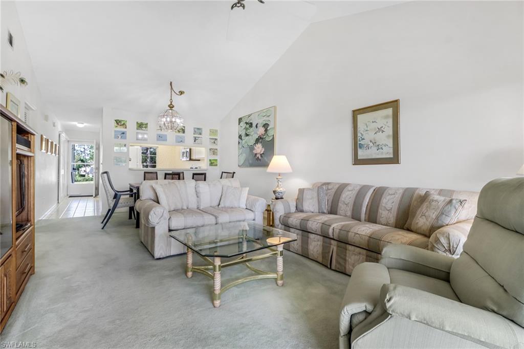 780 Augusta Boulevard, Unit C204 Naples, FL 34113 - Photo 10 of 40 a living room with furniture and a dining table with kitchen view