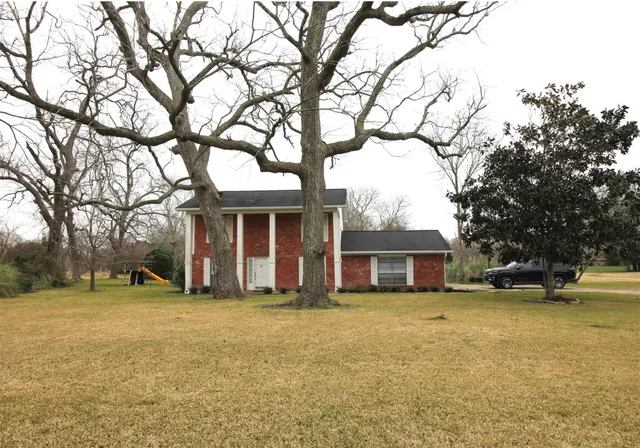 a view of a house with a yard and large trees