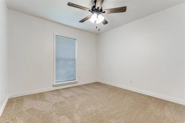 an empty room with a chandelier fan and windows
