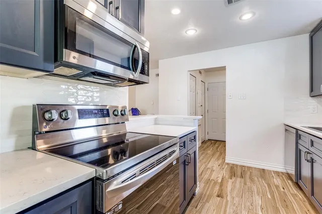 a kitchen view with wooden floor and stainless steel appliances