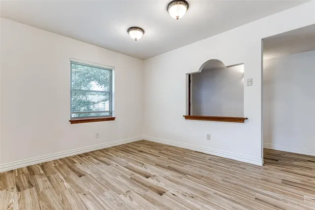 an empty room with wooden floor cabinet and windows