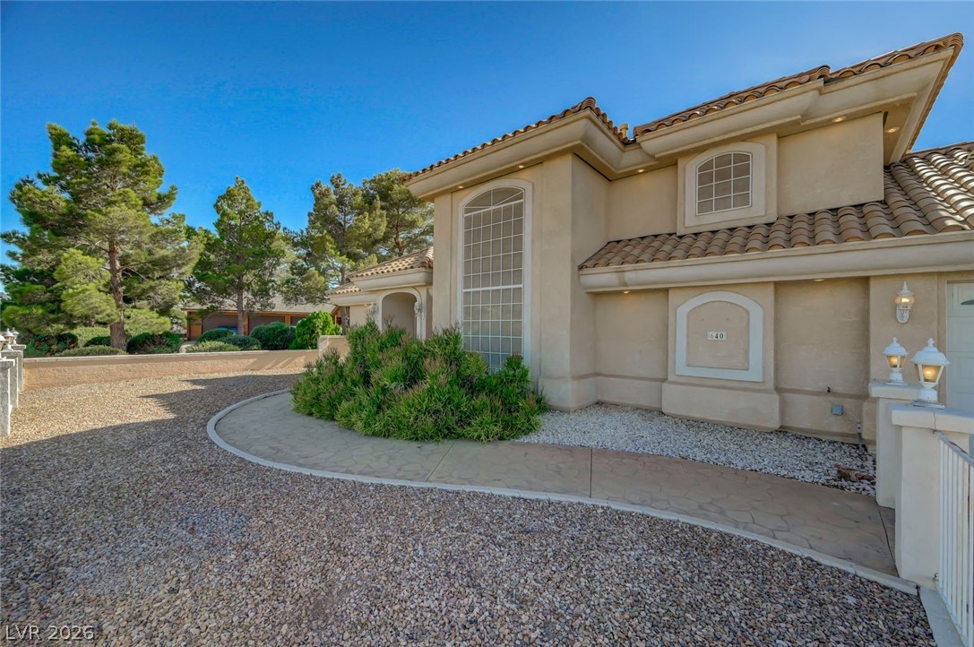 640 North Racetrack Road Henderson, NV 89015 - Photo 4 of 65 A graceful driveway leads to this architecturally distinctive stucco residence with arched windows and a tiled roof.