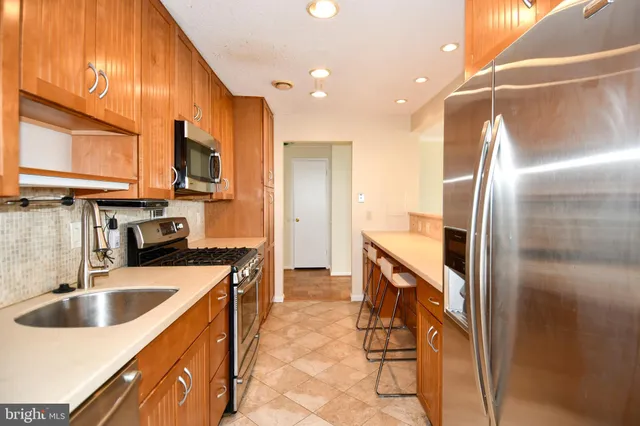 a kitchen with stainless steel appliances granite countertop a sink a stove and a refrigerator