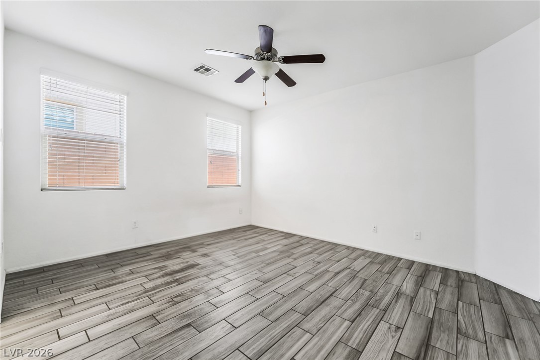 6245 Andover Wood Road Las Vegas, NV 89113 - Photo 17 of 37 A well-lit bedroom features cool-toned wood plank flooring and two windows for ample natural light.