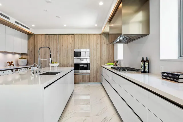a large white kitchen with stainless steel appliances granite countertop a lot of counter space and a sink