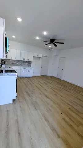 a view of a kitchen with kitchen island a sink wooden floor and a stove top oven