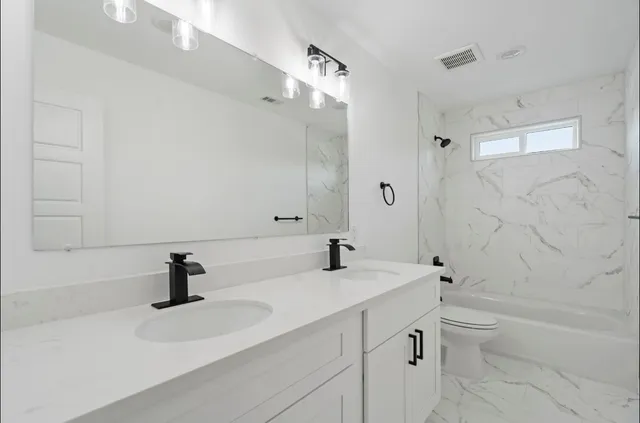 a bathroom with a double vanity sink toilet and shower