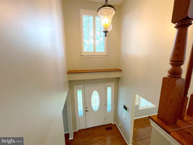 an empty room with wooden floor chandelier and windows