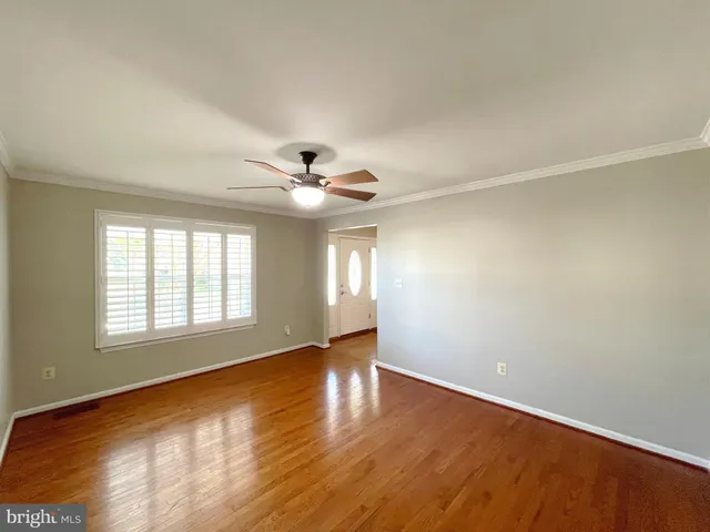 an empty room with wooden floor fireplace and windows