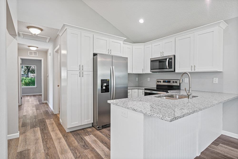 2885 North 8th Street St. Augustine, FL 32084 - Photo 11 of 35 a kitchen with a refrigerator a microwave a sink and cabinets