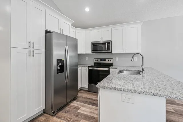 a kitchen with granite countertop a refrigerator and a sink