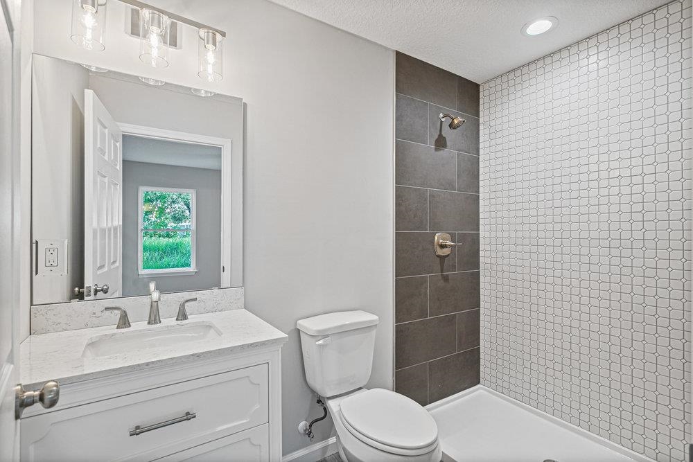 2885 North 8th Street St. Augustine, FL 32084 - Photo 25 of 35 a bathroom with a toilet a sink a mirror and shower