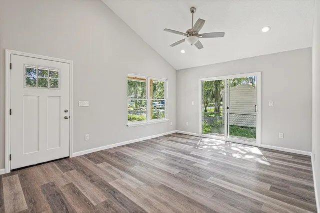 a view of an empty room with a window and wooden floor