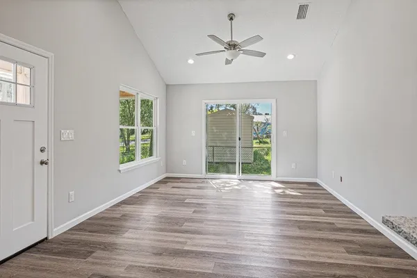 a view of an empty room with wooden floor and a window