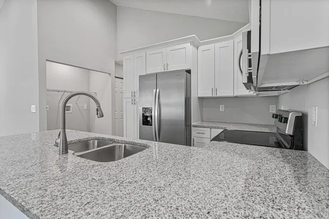 a kitchen with stainless steel appliances granite countertop a sink a refrigerator and a granite counter tops