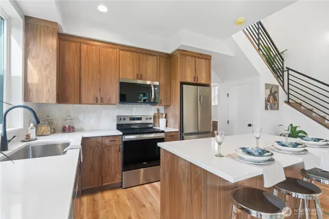 a kitchen with a sink dishwasher a stove a microwave oven with a dining table and chairs
