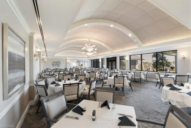 a living room with lots of furniture a chandelier and a view of kitchen