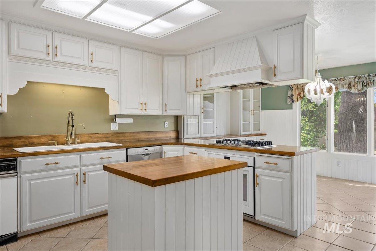 813 7th Street Rupert, ID 83350 - Photo 17 of 48 Spacious kitchen featuring white cabinetry, wood-finish countertops, a central island, built-in appliances, and a tile floor