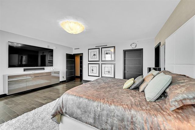 a bedroom with a large bed and a flat tv screen