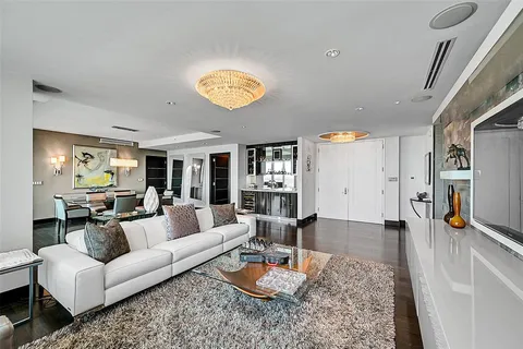 a living room with furniture kitchen view and a wooden floor