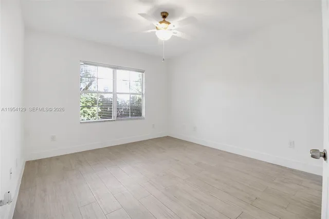 an empty room with a window and ceiling fan