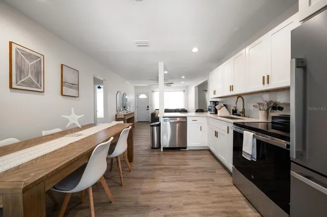 a kitchen with a refrigerator a stove a sink dishwasher and white cabinets with wooden floor