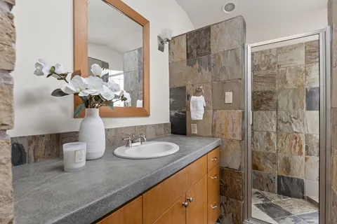 a bathroom with a granite countertop sink a toilet and shower