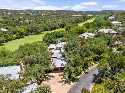 an aerial view of residential house with outdoor space and trees all around