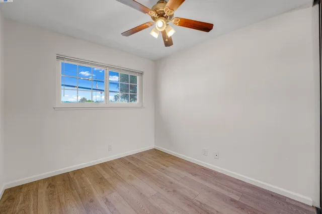 a view of an empty room with window and wooden floor